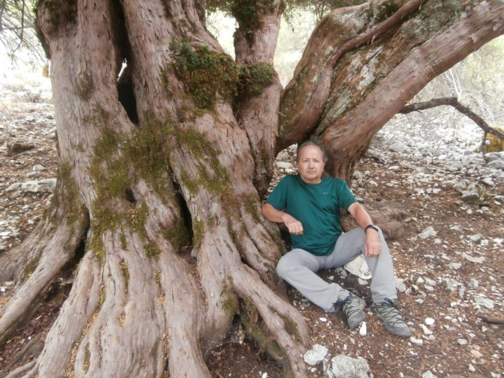 Fotografía de Alejandro sentado en el pie de un árbol.