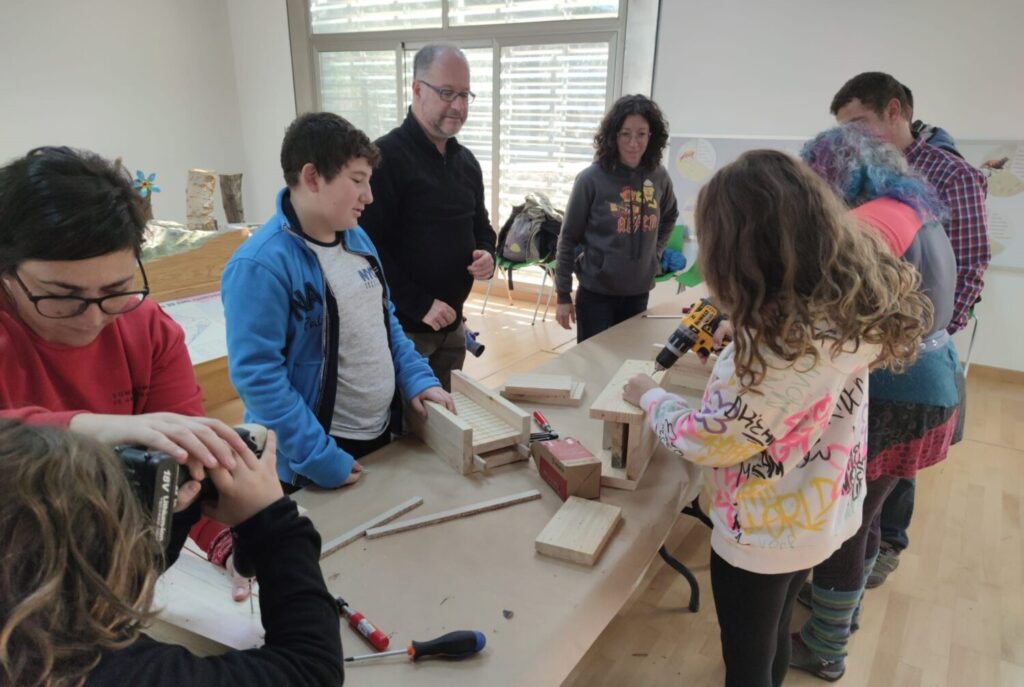 Voluntarios y voluntarias construyendo cajas nido