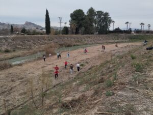 Alumnos y alumnas plantando y regando en la mota del río de Lorquí
